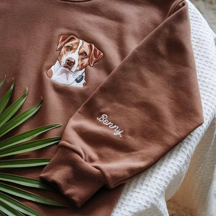 Close-up van een geborduurd hondenportret op een zacht sweatshirt. Perfect voor herdenking of als cadeau voor dierenliefhebbers.