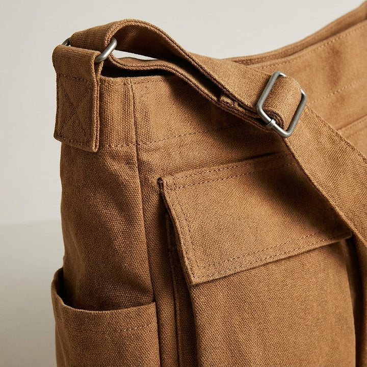 Close-up van de duurzame canvas stof van deze unisex schoudertas met verstelbare riem en vele vakken.