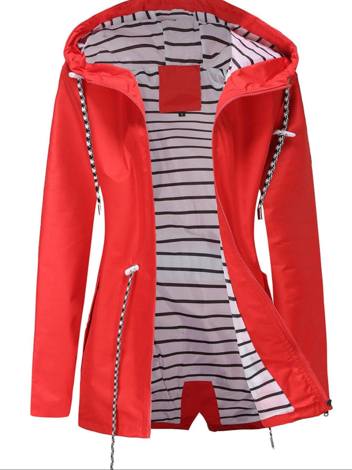 "Weerbestendige damesjas met capuchon in herfstkleuren, wind- en waterdicht, perfect voor regenachtig weer."