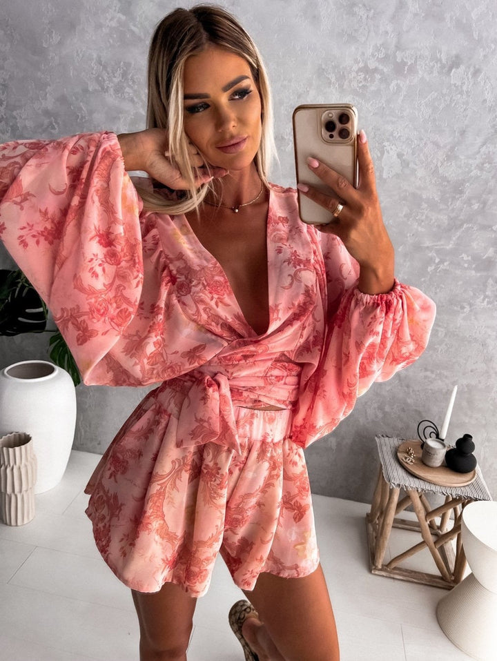 "Zomerse playsuit met V-hals, fruit- en bladmotieven, kleurrijke tropische print, accentueert silhouet en biedt comfort."