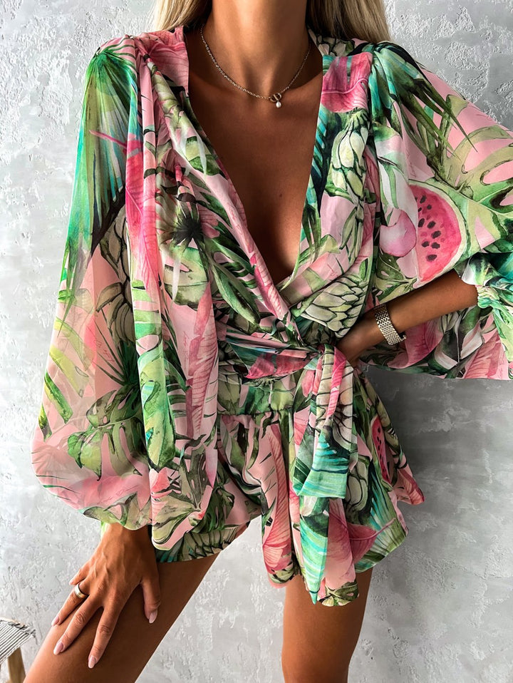 "Zomerse playsuit met V-hals, fruit- en bladmotieven, kleurrijke tropische print, accentueert silhouet en biedt comfort."