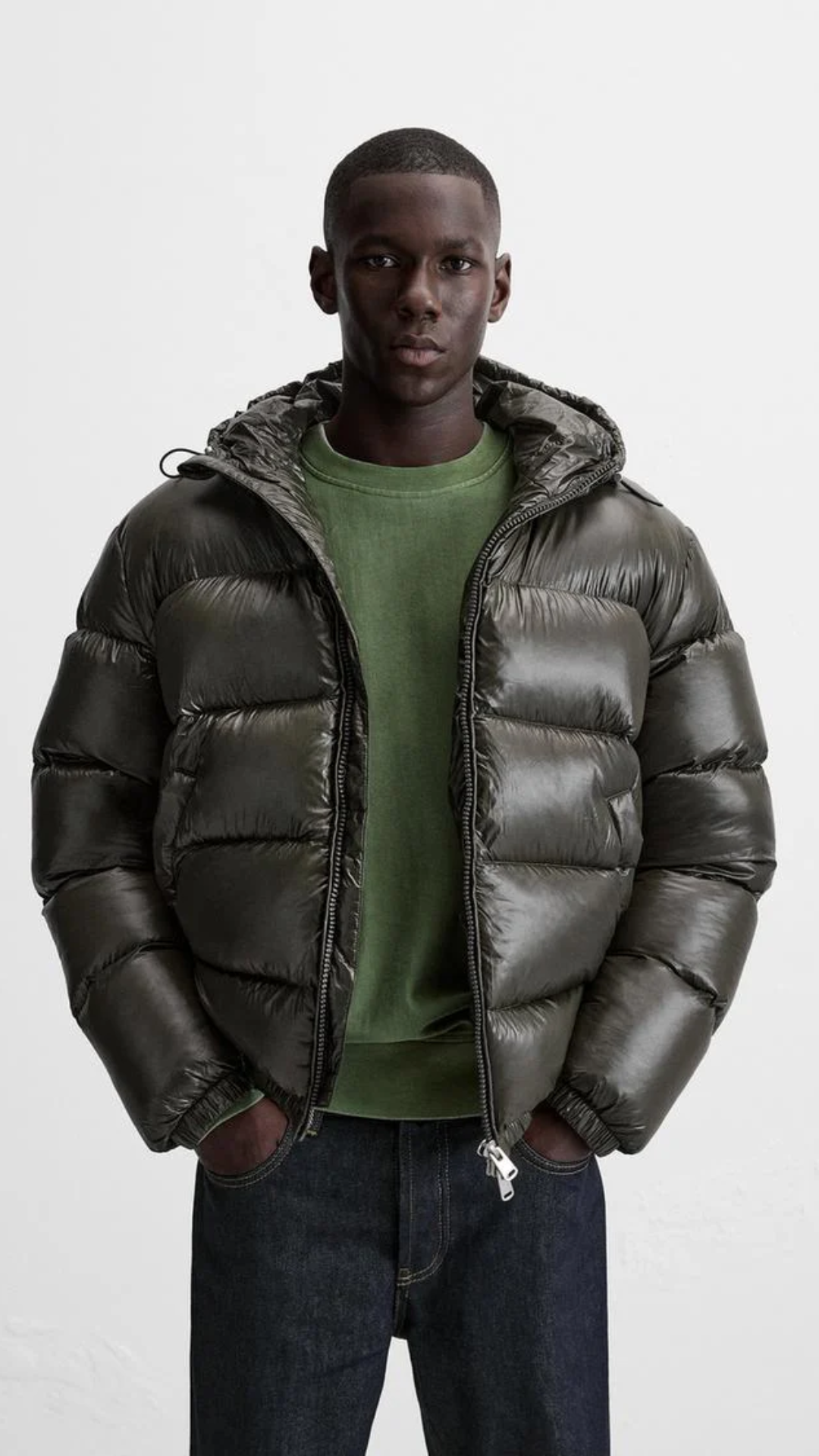 Man poseert in een warm en modieus groen winterjack, klaar voor de koude dagen.