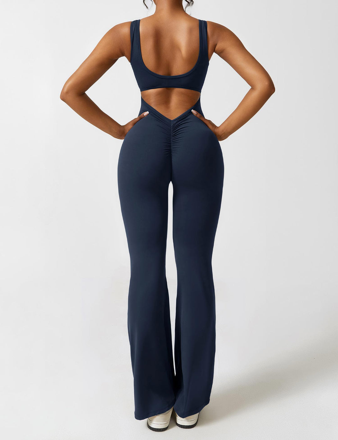 Donkerblauwe jumpsuit met V-rug, flared pijpen en subtiel shaping effect.