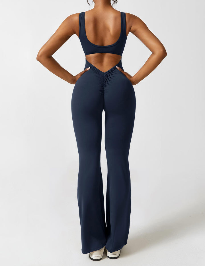 Donkerblauwe jumpsuit met V-rug, flared pijpen en subtiel shaping effect.